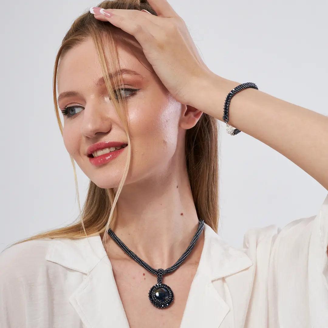 Model wearing a handcrafted amethyst and onyx heart necklace, featuring natural purple gemstones that promote healing, calmness, and spiritual growth.