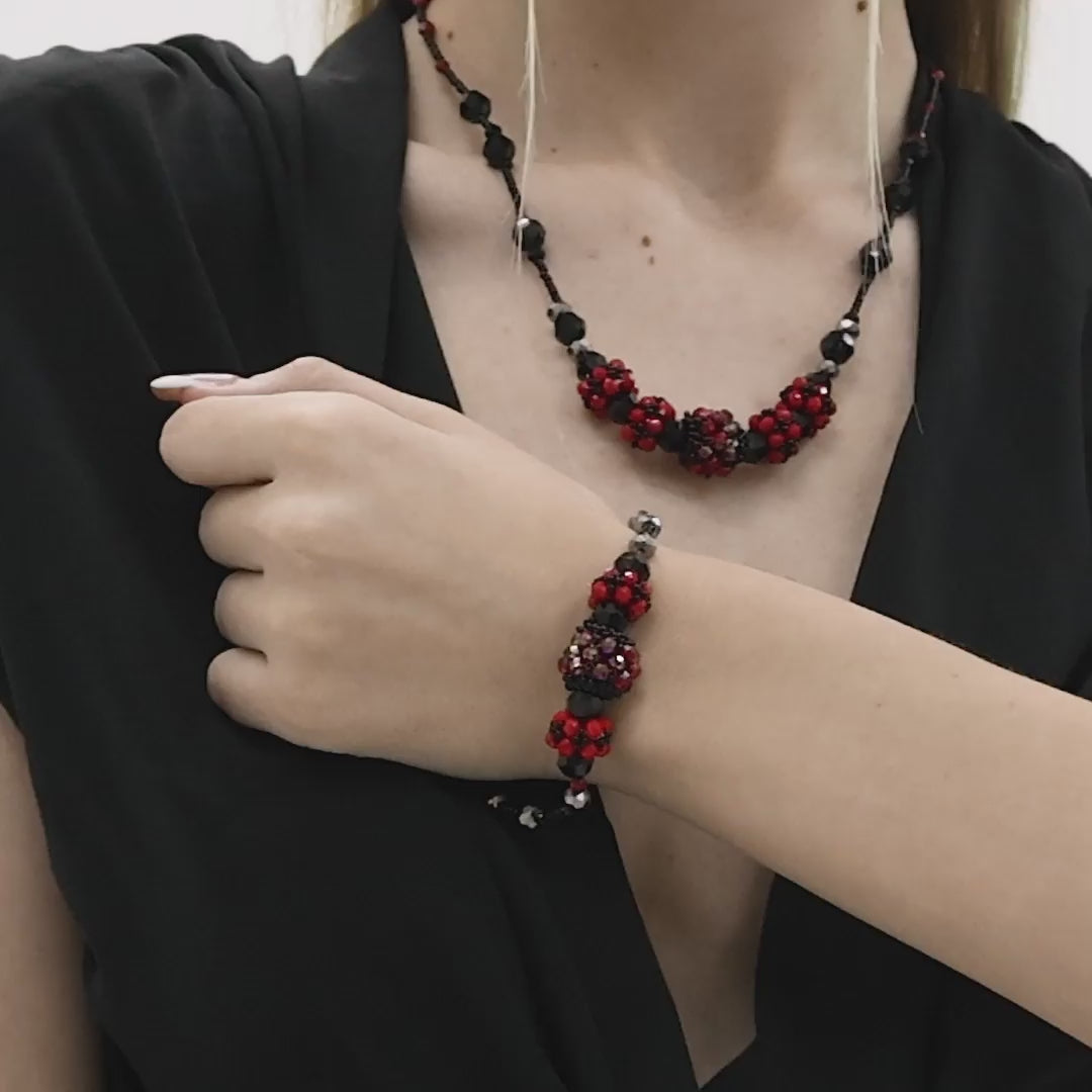 Handmade Black Pearl Jewelry Set
A woman wearing a handcrafted red and black beaded jewelry set, featuring a floral design. The set includes a matching necklace and bracelet, both intricately made with small beads in red and black tones, creating an elegant and bold look. The jewelry adds a sophisticated touch to her outfit, showcasing the detailed craftsmanship.